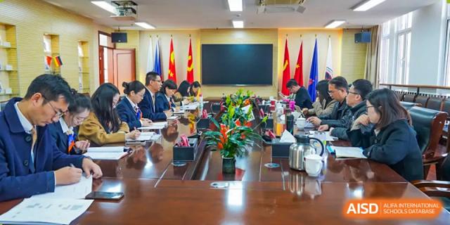 A group of adults is seated around a large conference table in a meeting room, at Changshu Lunhua Foreign Language School.
