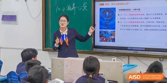 A female teacher gestures towards a projector screen in a classroom, at Changshu Lunhua Foreign Language School.