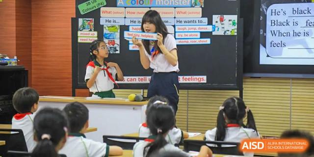 A female teacher points to a diagram on a whiteboard in front of a class, at Changshu Lunhua Foreign Language School.