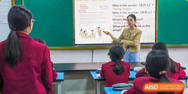 A female teacher points to a presentation on a screen in front of a class, at Changshu Lunhua Foreign Language School.