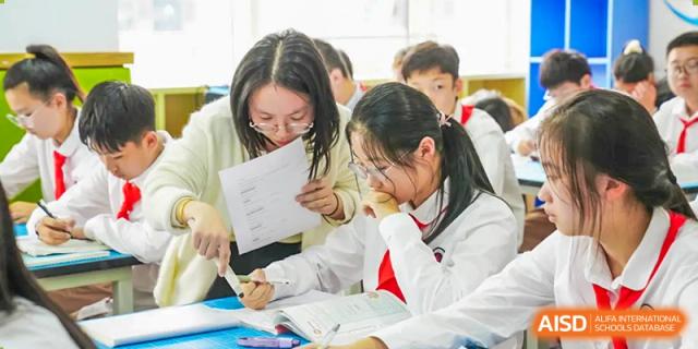 A group of female students studies together, looking at papers at their desks, at Changshu Lunhua Foreign Language School.