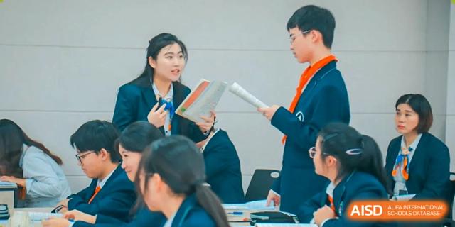 Two female students and one male student are standing together, with one of the students holding a book, at Changshu Lunhua Foreign Language School.