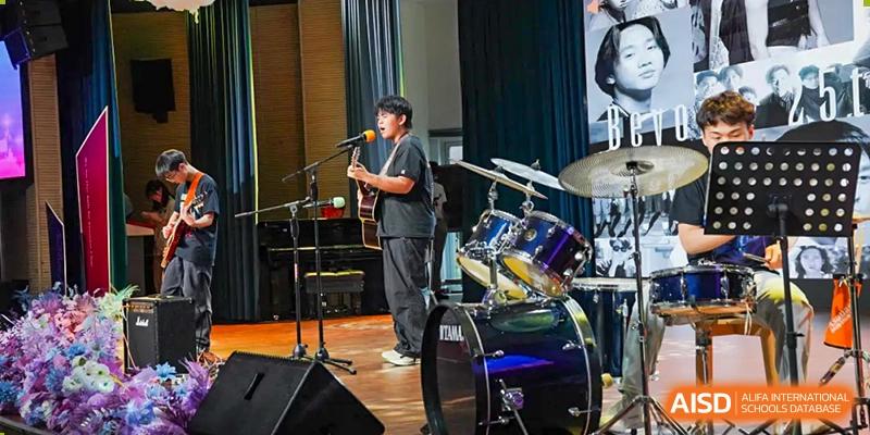 A male student plays an acoustic guitar and sings into a microphone on a stage, at Changshu Lunhua Foreign Language School.