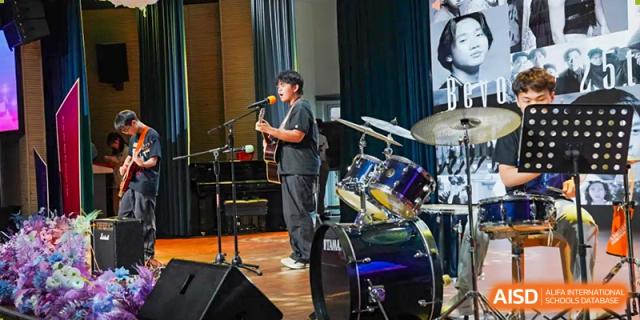 A male student plays an acoustic guitar and sings into a microphone on a stage, at Changshu Lunhua Foreign Language School.