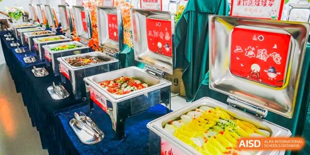 A buffet table with various dishes in metal serving trays, at Changshu Lunhua Foreign Language School.