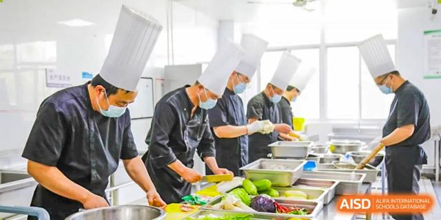 Chefs in a kitchen prepare food, at Changshu Lunhua Foreign Language School.