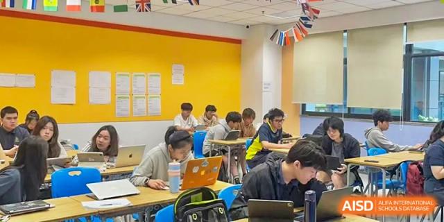 Students working independently on laptops and in notebooks during a quiet classroom session at Chiway Bilingual School Xiamen.