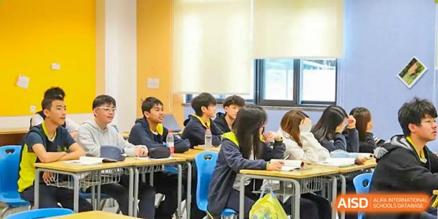 Students from Chiway Bilingual School Xiamen listening attentively while seated at desks in a brightly lit classroom.