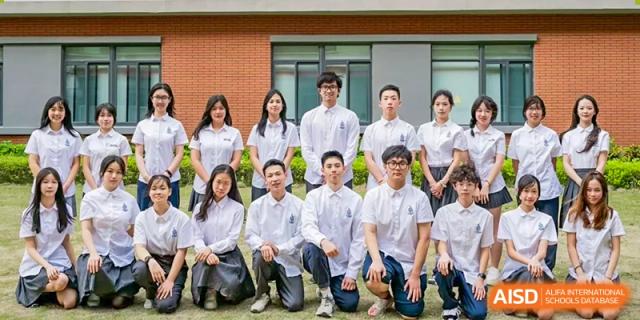 A large group of students from Chiway Bilingual School Xiamen wearing white shirts and kneeling or standing for a group portrait outdoors.