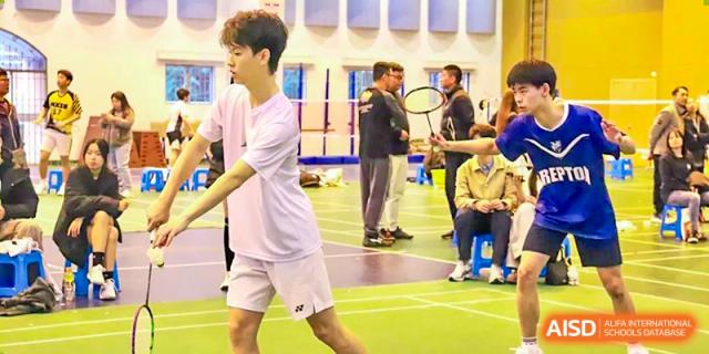 A student at Chiway Bilingual School Xiamen playing badminton, mid-swing on an indoor court.