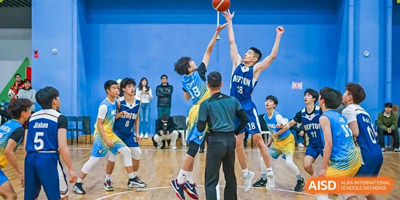 A dynamic moment during a basketball game at Chiway Bilingual School Xiamen, showing players jumping to block a shot near the basket.