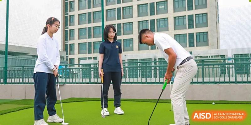 A female student and a male coach at Chiway Bilingual School Xiamen practicing golf on a sunny lawn area.