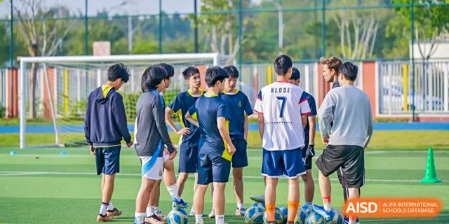Students from Chiway Bilingual School Xiamen wearing sports jerseys and gathering on an outdoor turf field.