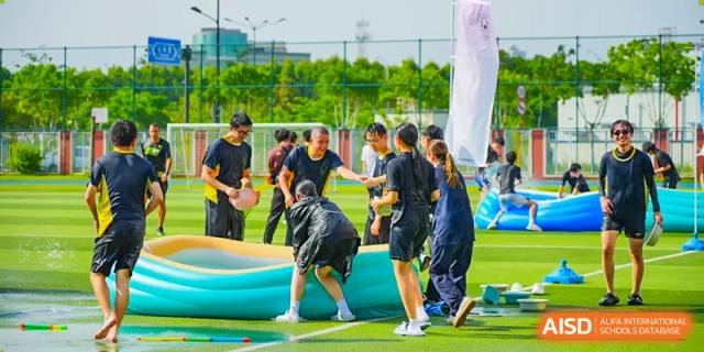 Students from Chiway Bilingual School Xiamen participating in an outdoor team-building or water activity on a green lawn.