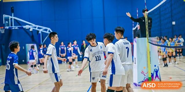 Students from Chiway Bilingual School Xiamen in white and blue uniforms high-fiving on an indoor basketball or volleyball court after a game.