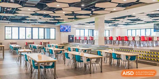 The spacious, modern, and brightly lit student cafeteria or dining hall at Chiway Bilingual School Xiamen with colorful chairs.