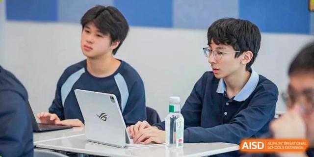 Two students from Dipont Huayao Collegiate School Kunshan are sitting at a table with a laptop.