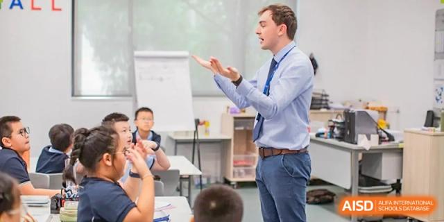An international teacher from Dipont Huayao Collegiate School Kunshan stands in a classroom, using hand gestures while teaching students.