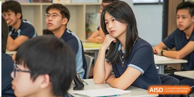A student from Dipont Huayao Collegiate School Kunshan is seated at a desk in a classroom, listening to the teacher.