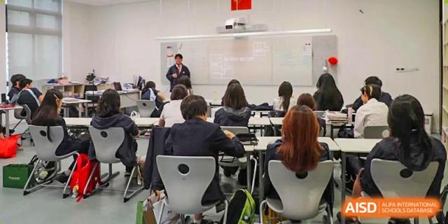 A teacher from Dipont Huayao Collegiate School Kunshan stands in front of a class, writing on a whiteboard.