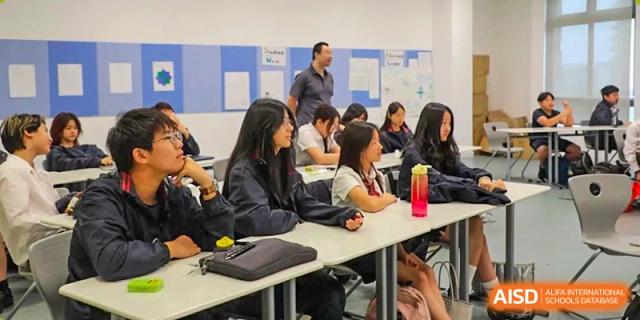 Students from Dipont Huayao Collegiate School Kunshan are seated in a classroom, listening to their teacher.