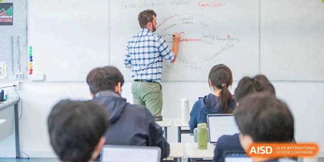 A teacher from Dipont Huayao Collegiate School Kunshan writes on a whiteboard with students seated at their desks.