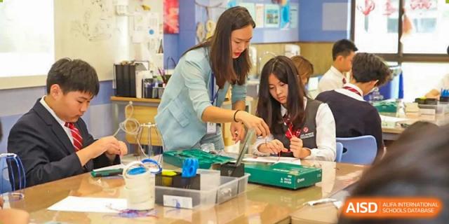 A teacher from Dipont Huayao Collegiate School Kunshan is helping students with a hands-on project at a table.