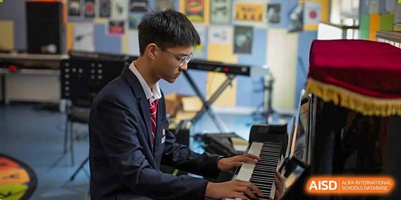 A student from Dipont Huayao Collegiate School Kunshan, dressed in a suit, plays the piano.