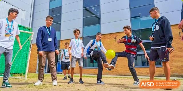 Students from Dipont Huayao Collegiate School Kunshan are playing football and doing kick-ups on a field.