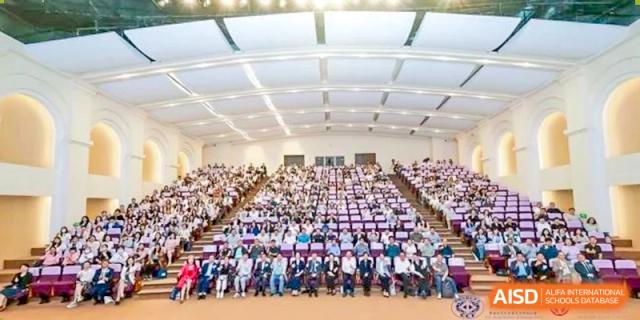 A large group of students from Dipont Huayao Collegiate School Kunshan is seated in an auditorium, attending an event.