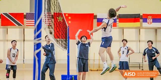 Students from Dipont Huayao Collegiate School Kunshan are playing volleyball in a gymnasium.