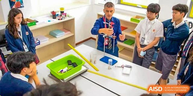 A teacher from Dulwich College Beijing is demonstrating a science experiment to a class.