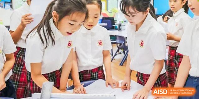 Students from Dulwich College Beijing are collaborating on a project together at a desk.