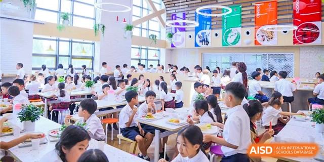 Students eating lunch in the bright and busy cafeteria at Dulwich College Beijing.