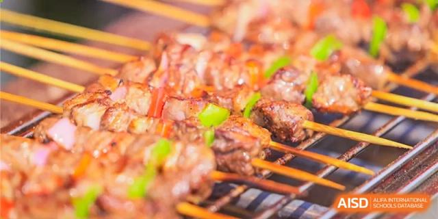 A close-up shot of grilled meat and green pepper skewers cooking on a grill at a food event at Dulwich College Beijing.