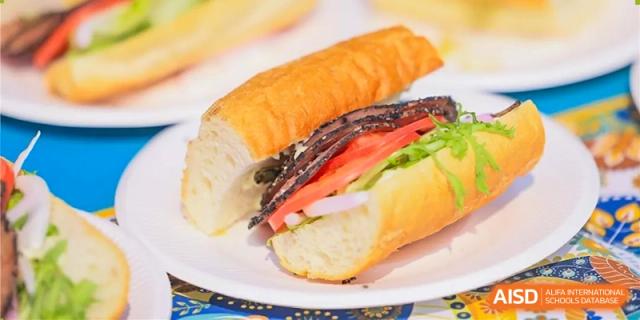 A detailed image of a fresh sandwich with meat, lettuce, and tomato on a white plate at a food fair at Dulwich College Beijing.