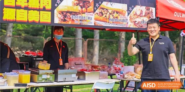 A vendor stands behind a food stall at an outdoor event at Dulwich College Beijing.