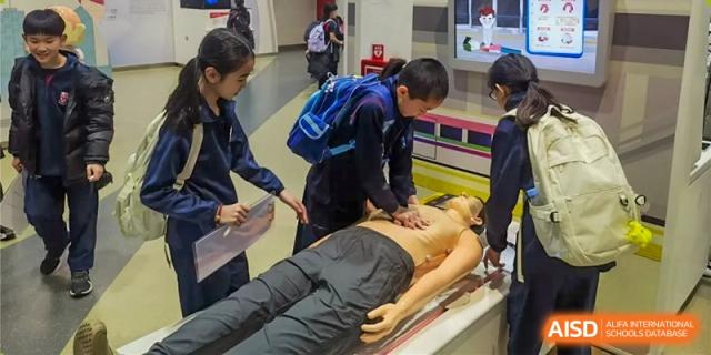 Students learn CPR using a training dummy during a first aid class at Dulwich College Beijing.