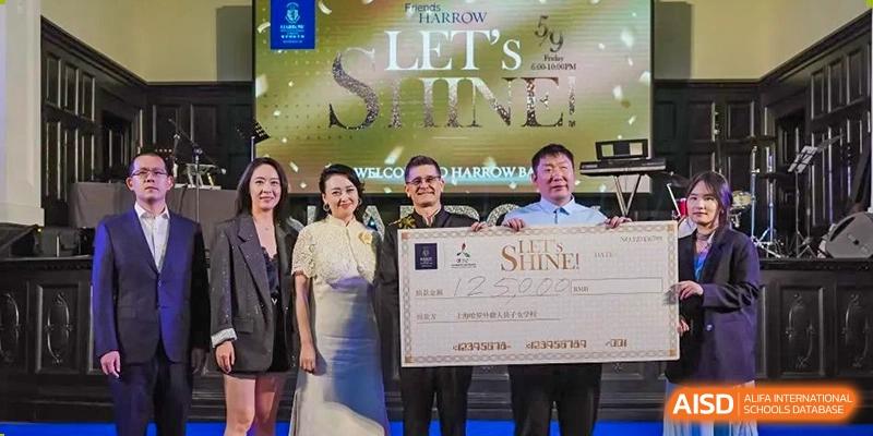 Harrow International School Shanghai students and faculty holding a large check with the words 'Let's Shine' in the background.