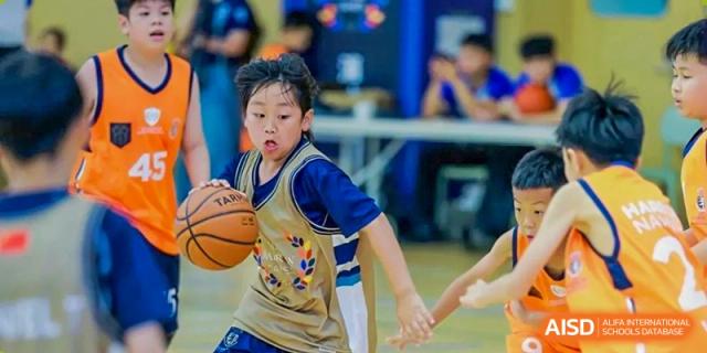 A young male student from Harrow International School Shanghai dribbling a basketball during a game.