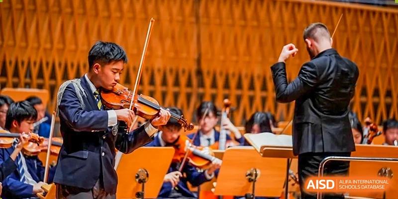A group of Harrow International School Shanghai students playing violins in an orchestra.