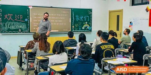 A classroom scene with students facing the front and a blackboard filled with writing and a greeting in Chinese characters at TheNo.2 High School Of East China Normal University (HSEFZ).