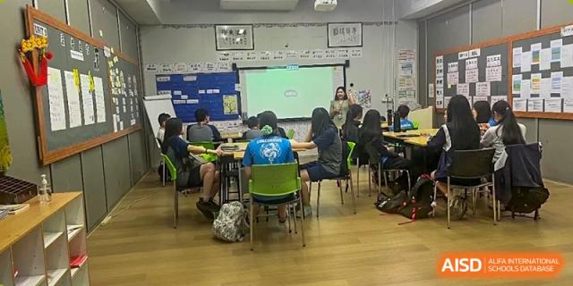 A group of students seated in a classroom with a large digital whiteboard display in the background at The No.2 High School Of East China Normal University (HSEFZ).