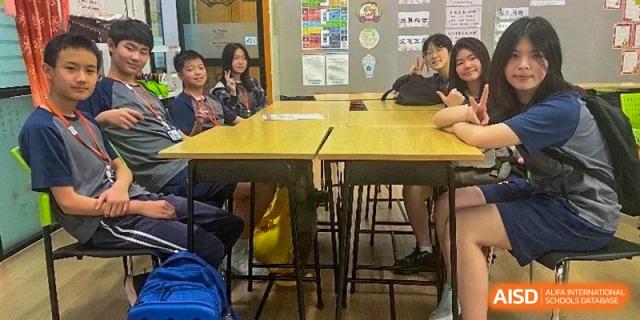 A group of students and teachers seated around a table in a classroom, engaged in a discussion or lesson at The No.2 High School Of East China Normal University (HSEFZ).