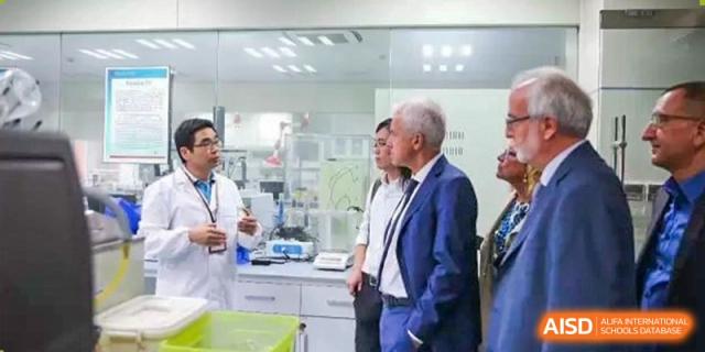 A staff member or teacher speaking with a distinguished guest or administrator in a modern science laboratory at The No.2 High School Of East China Normal University (HSEFZ).