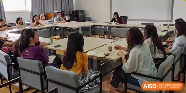 Students or adults seated at tables in a study hall or common area, working independently on laptops at The No.2 High School Of East China Normal University (HSEFZ).