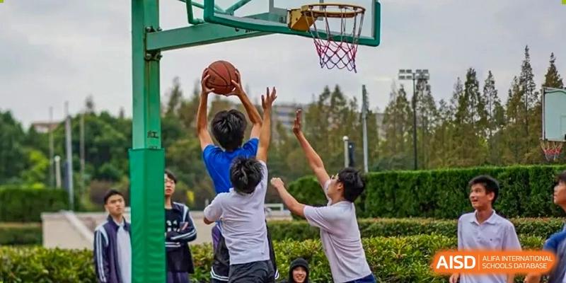 Students competing for a rebound or block during an outdoor basketball game at TheNo.2 High School Of East China Normal University (HSEFZ).
