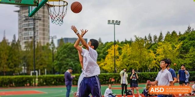 A student shooting a basketball outdoors on the court during a game or practice at The No.2 High School Of East China Normal University (HSEFZ).