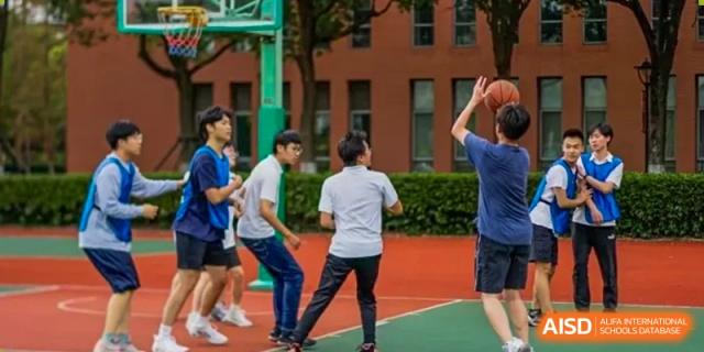 Students wearing white and blue shirts standing on the basketball court during a casual sports session at The No.2 High School Of East China Normal University (HSEFZ).