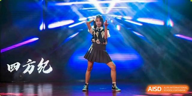 A female student in a skirt and shirt posing under bright blue spotlights during a talent show or dance performance at The No.2 High School Of East China Normal University (HSEFZ).